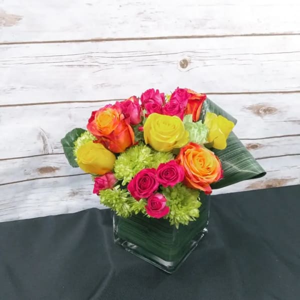 Bright mixed rose bouquet in a square glass vase
