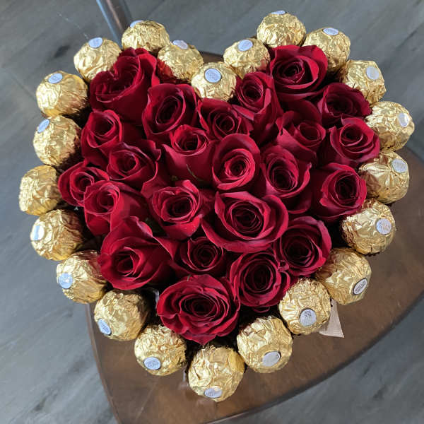 Heart-shaped bouquet of red roses surrounded by gold-wrapped chocolates