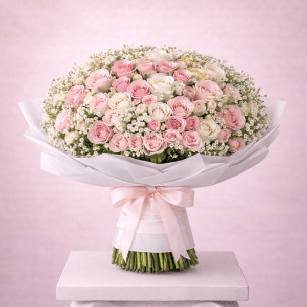Large bouquet of pink and white roses wrapped in white paper with a ribbon