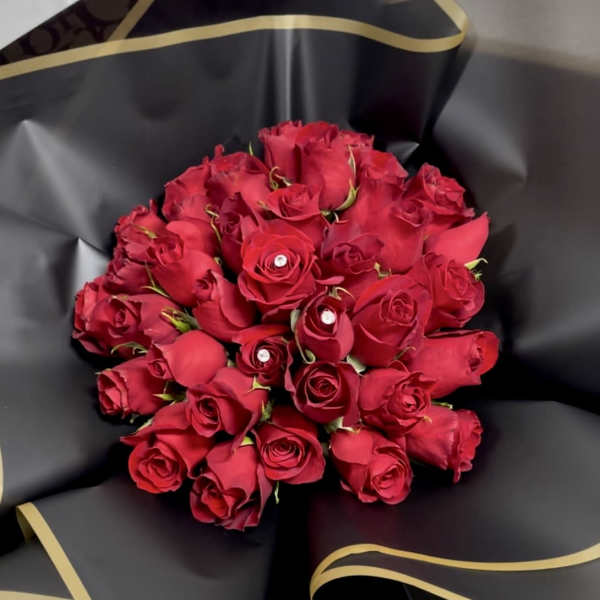 Bouquet of red roses wrapped in black paper with gold trim