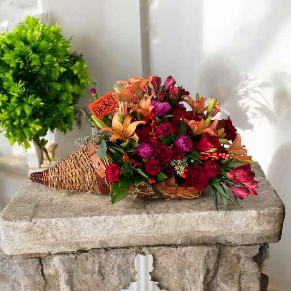 Basket arrangement with red and orange flowers and a small thank-you sign