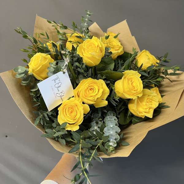 Bouquet of yellow roses wrapped in brown paper