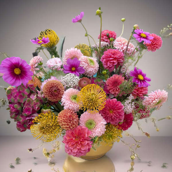 Pink and yellow mixed flower arrangement in a low vase