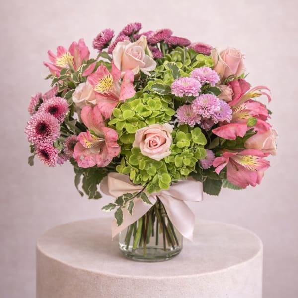 Pink and green bouquet of roses, alstroemeria, and mums in a glass vase