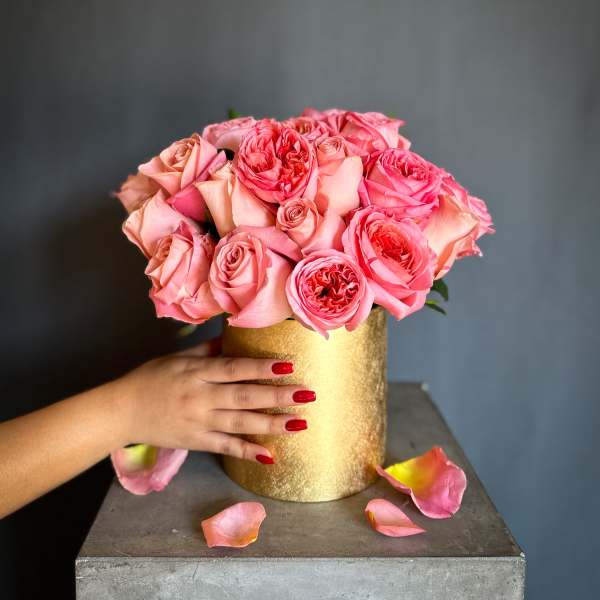 Pink roses arranged in a gold cylindrical vase