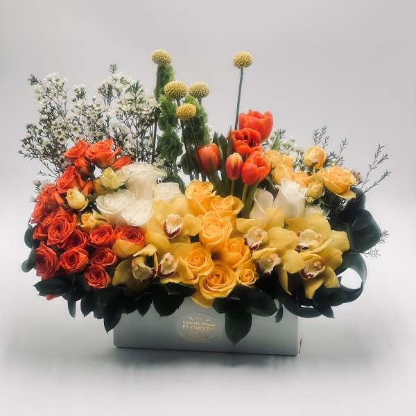 Mixed bouquet of orange, yellow, and white flowers in a gray box