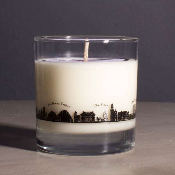 White candle in a clear glass tumbler with a city skyline design