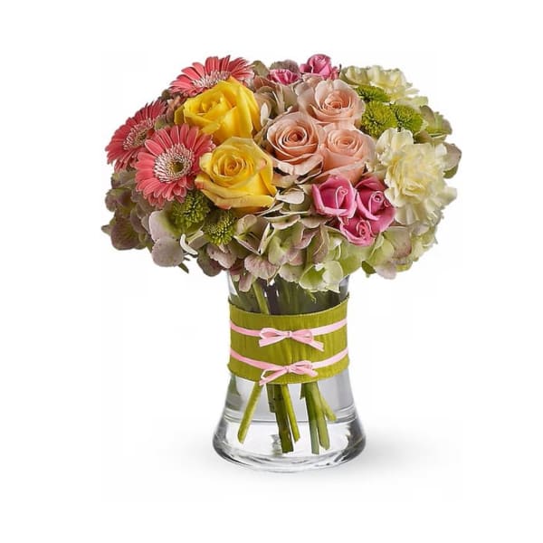 Mixed bouquet of roses, gerbera daisies, and hydrangeas in a glass vase