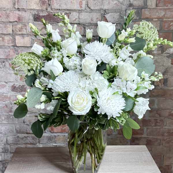White floral arrangement in a clear glass vase on a table