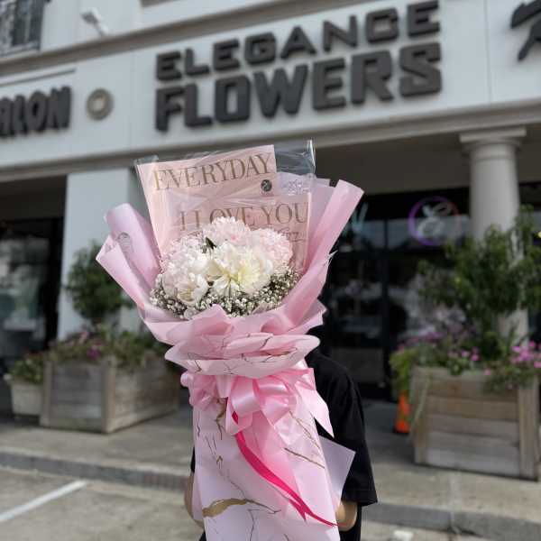 Pink-wrapped bouquet of white and pale pink flowers