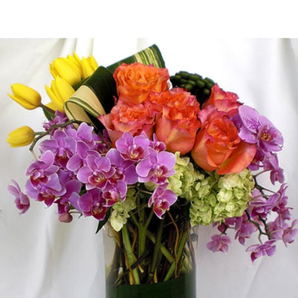 Bouquet of orange roses, purple orchids, and yellow tulips in a glass vase