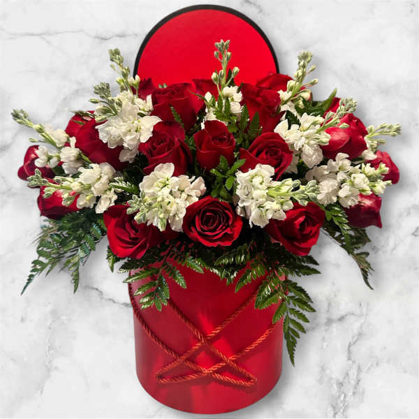 Red roses and white flowers in a red hatbox with greenery