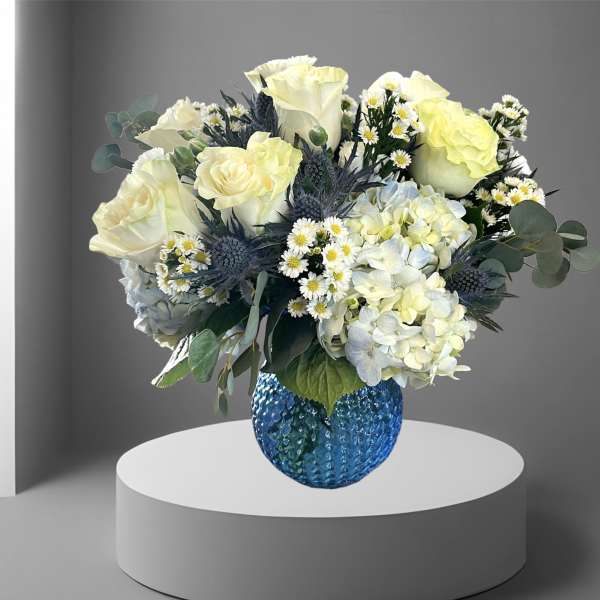 Bouquet of pale roses and hydrangeas in a blue glass vase