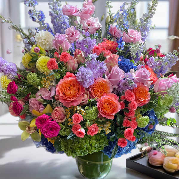 Large mixed bouquet of roses, hydrangeas, and lavender flowers in a glass vase