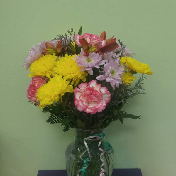 Bouquet of yellow chrysanthemums and pink carnations in a glass vase