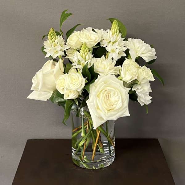 White roses and carnations arranged in a clear glass vase