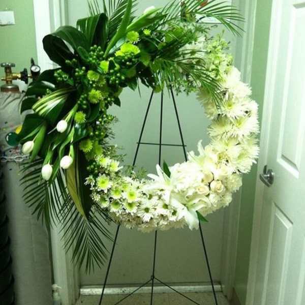 White and green floral wreath on a black stand