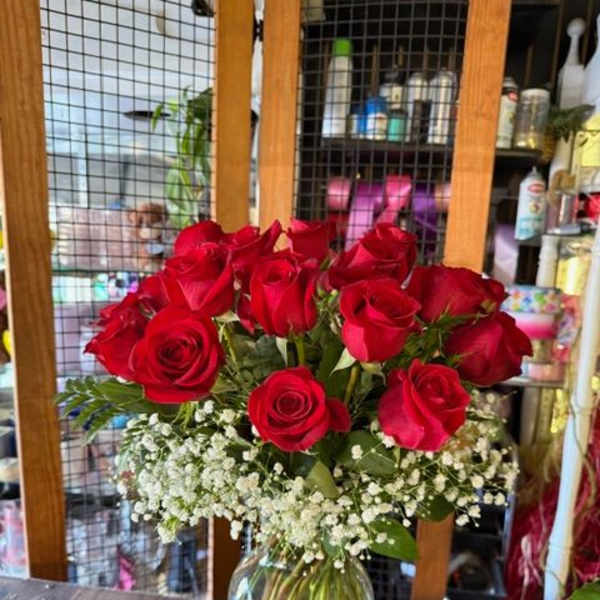 Red roses arranged in a clear glass vase with white baby's breath.