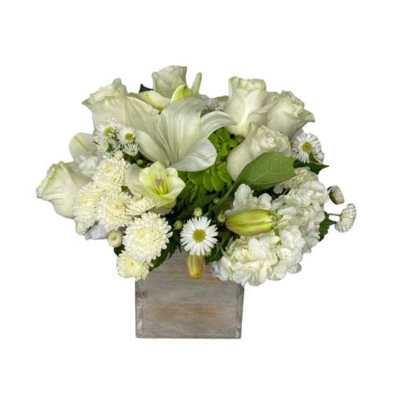 White floral arrangement in a square vase with lilies and daisies