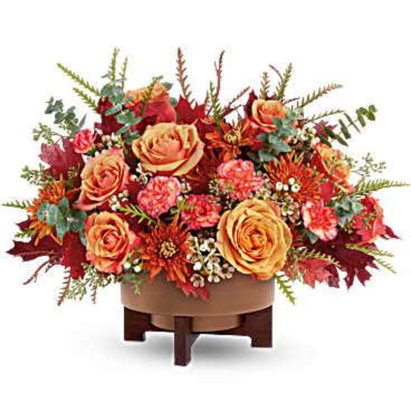 Autumn floral arrangement with orange roses in a low wooden stand