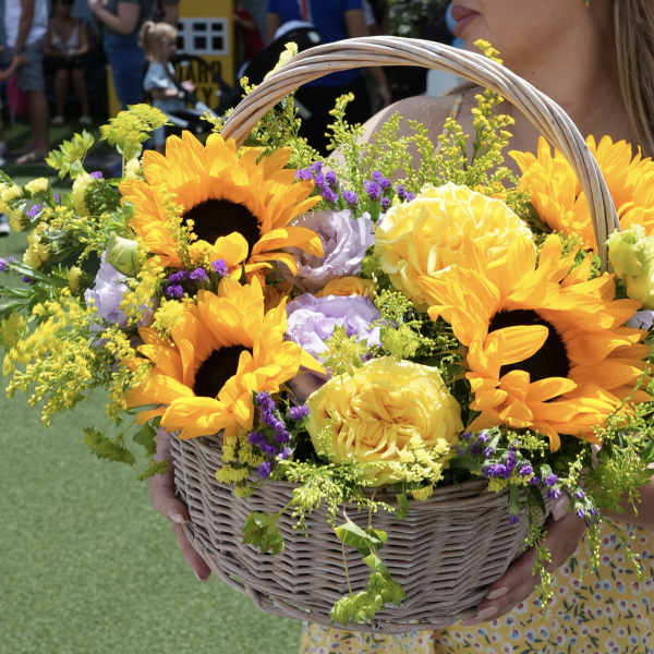 Basket of sunflowers and yellow roses with purple accents