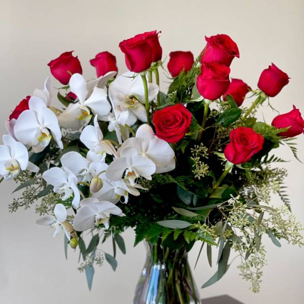 Red roses and white orchids in a clear glass vase