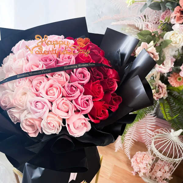 Bouquet of pink and red roses wrapped in black paper