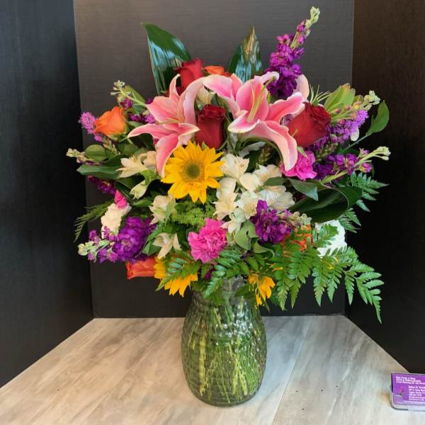 Mixed bouquet of lilies, roses, and daisies in a glass vase