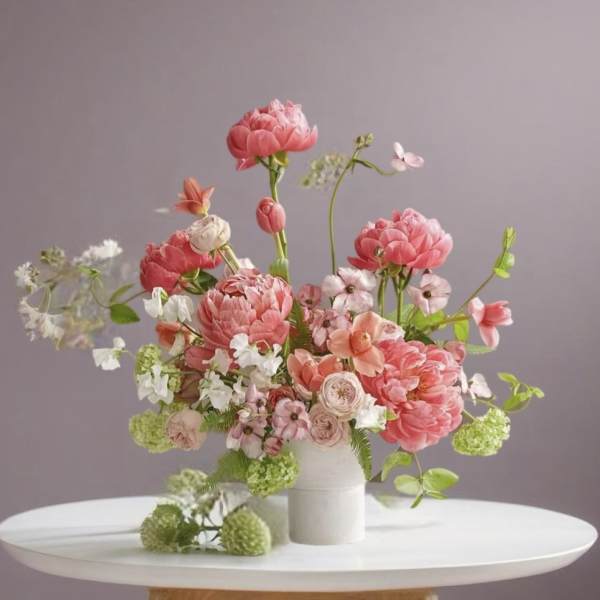 Pink and peach floral arrangement in a white vase