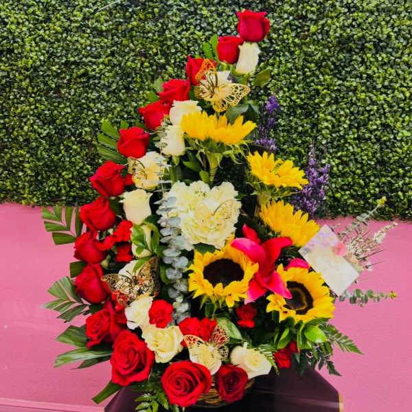 Tall floral arrangement with red and white roses and yellow sunflowers in a basket