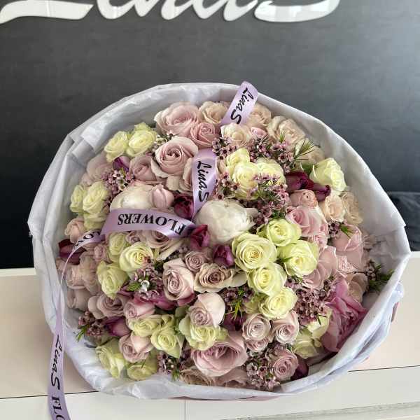Large bouquet of pale pink and cream roses wrapped in white paper