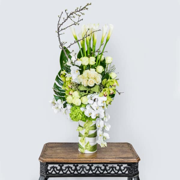 Tall white and green floral arrangement in a ribbon-wrapped vase