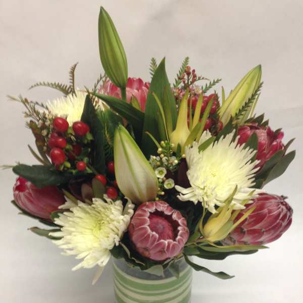 Bouquet of pink protea and white chrysanthemums in a striped glass vase