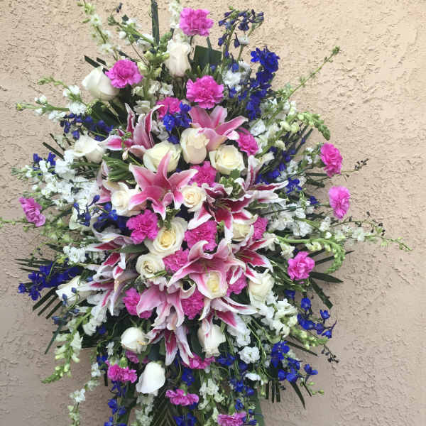 Large standing spray of pink lilies, white roses, and blue flowers