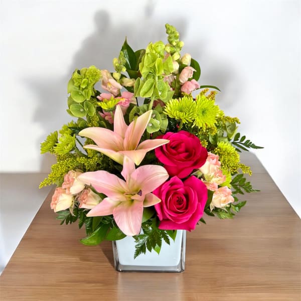 Pink lilies and hot pink roses in a square glass vase