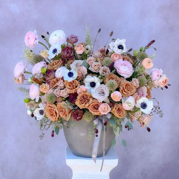 Large pastel bouquet of roses and anemones in a gray vase