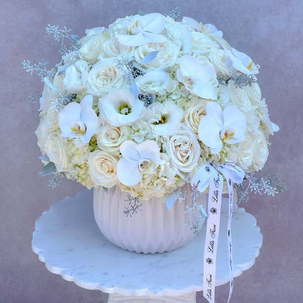 White rose and orchid arrangement in a ribbed white vase