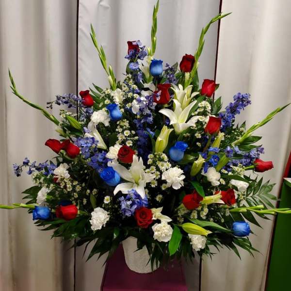 Large floral spray with red, white, and blue flowers in a white container