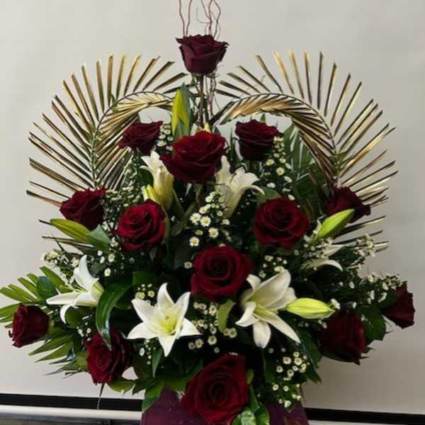 Red roses and white lilies arranged in a tall display with gold fan accents