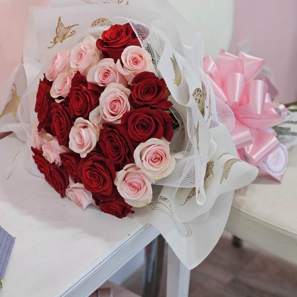 Bouquet of red and pale pink roses wrapped in white paper
