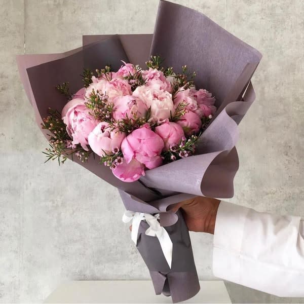 Hand-tied bouquet of pink peonies wrapped in lavender paper