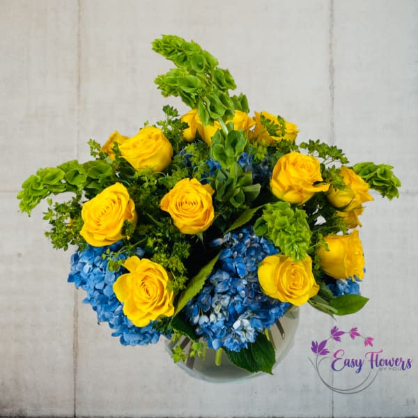 Yellow roses and blue hydrangeas in a glass vase