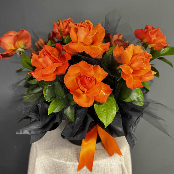 Orange roses arranged with black wrap and ribbon