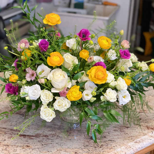 Mixed bouquet of white, yellow, and purple roses in a glass vase