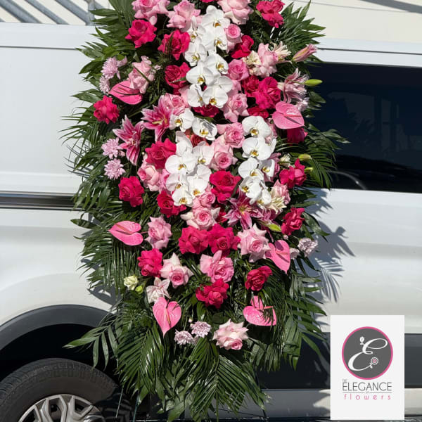 Tall pink and white standing spray with roses, lilies, orchids, and anthuriums on a metal easel.