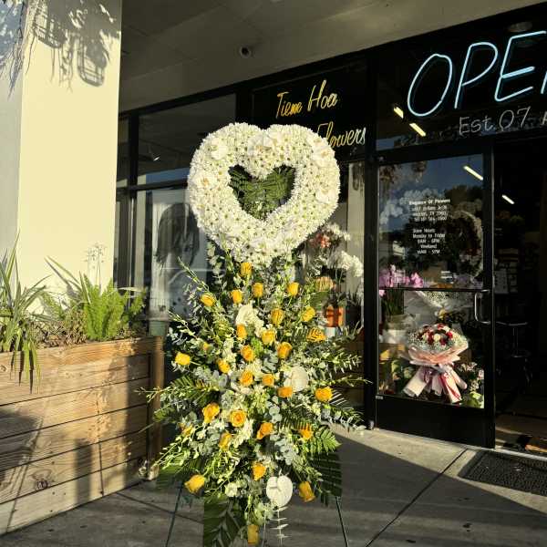 Heart-shaped standing floral tribute with white and yellow flowers