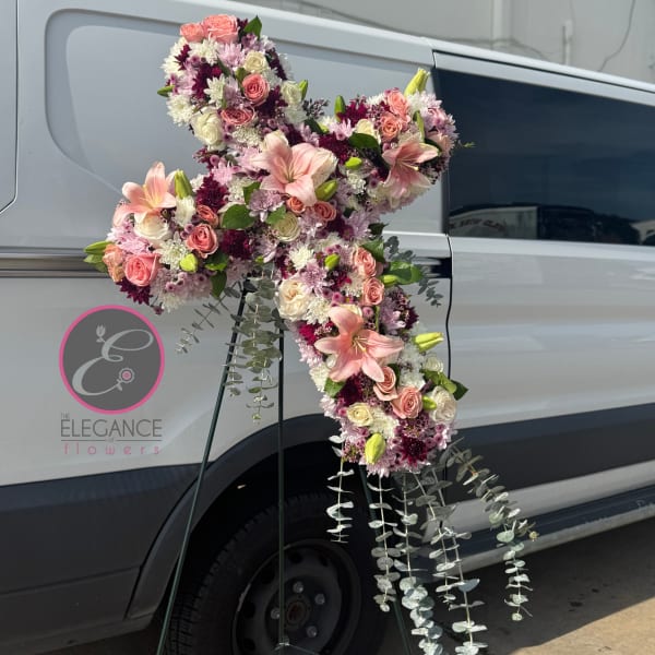 Large pink and white floral cross on a stand