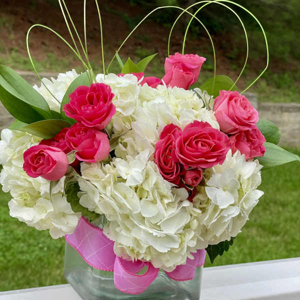 Pink roses and white hydrangeas in a glass vase with ribbon