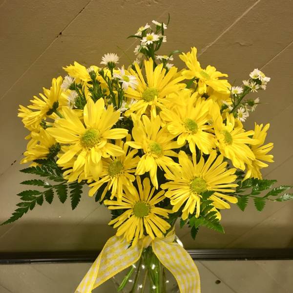 Yellow daisy bouquet in a clear glass vase with a checked ribbon