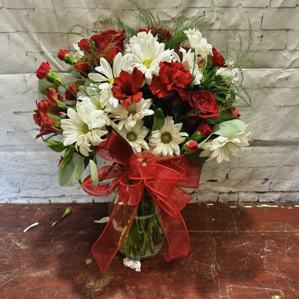 Bouquet of red and white flowers in a glass vase with a red ribbon